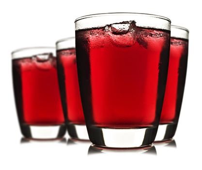 Three glasses of red fruit juice with ice on white background