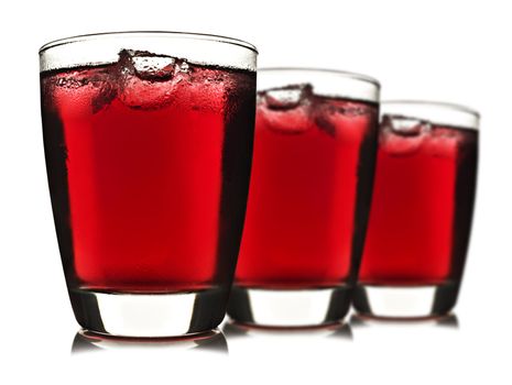 Three glasses of red fruit juice with ice on white background