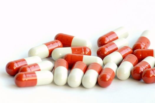 Closeup view of red-and-white medicine capsules on white background
