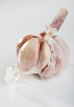 A ball of garlic half peeled on white background