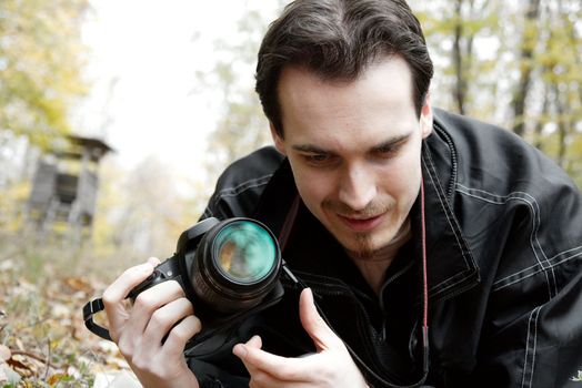 Photographer with his camera looking at the ground outdoors