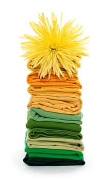 Joyful spring laundry. Flower on top of green and yellow folded clothes.