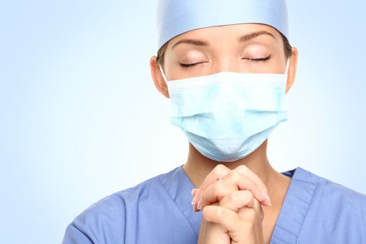 Doctor praying for help. Young woman medical doctor surgeon or nurse portrait.
