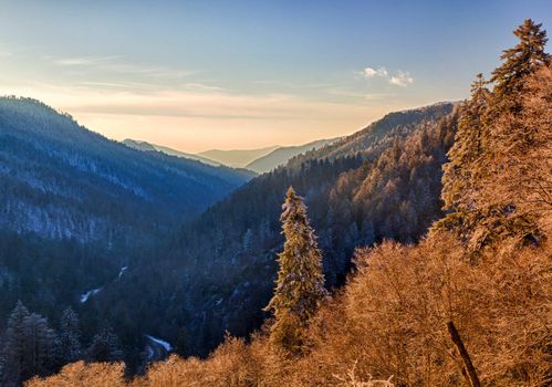 Sun setting in valley in Smokies as snow covers the branches of trees