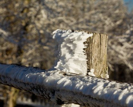 Snow blown into sharp shapes on old wooden fence post