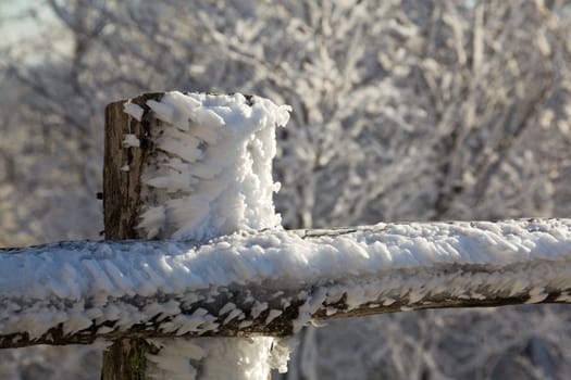 Snow blown into sharp shapes on old wooden fence post