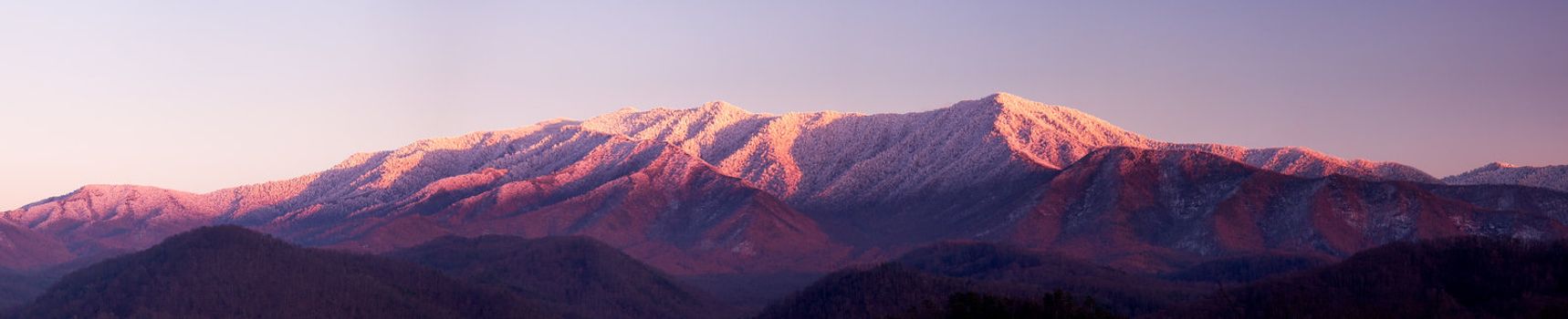 Sun setting on the Smoky mountains covered in snow above the town of Gatlinburg at dusk