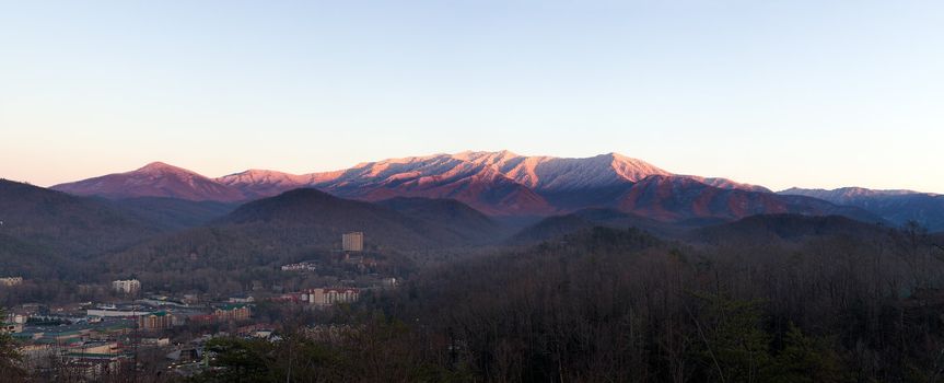 Sun setting on the Smoky mountains covered in snow above the town of Gatlinburg at dusk