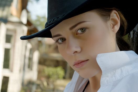 Portrait of a woman in a white shirt and cowboy hat on a ranch.