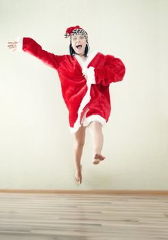 Jumping lady in the red Santa Claus costume indoors. Natural light and colors