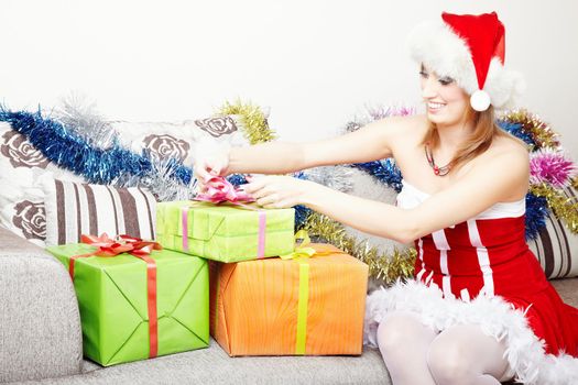 Smiling lady in the red furry Santa Claus costume and hat preparing Christmas gifts