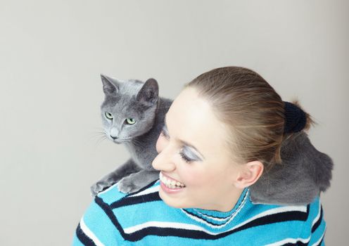 Cat playing on the back of laughing woman indoors