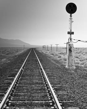 A black and white photograph of an old fashioned railroad light and railroad.