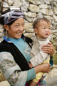 A Hmong woman with her baby blue. Her hairstyle is very neat. This ethnic group does not cap, but women have this style typical of Hmong blue with blue tape wrapped around the knot of hair flattened by taking silver clips. A silver comb is thrust into the hair before
