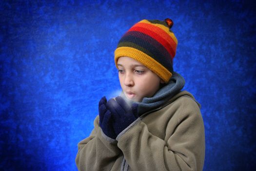 Boy trying to warm his hands with his breath in winter outfit. Look at my gallery for more winter images