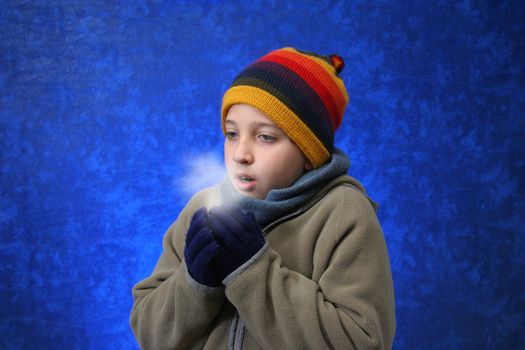 Boy trying to warm his hands in winter outfit. Look at my gallery for more winter images
