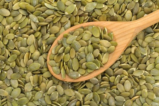 Wooden spoon filled with pumpkin seeds in natural light