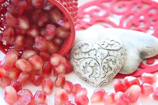 Pomegranite seeds spilling from a decorative container with ceramic hearts