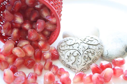 Pomegranite seeds spilling from a decorative container with ceramic hearts