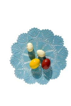 Four Easter eggs on a blue knitted napkin isolated on a white background