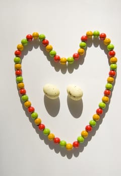 Easter eggs and heart forms colored beads around them isolated on a white background