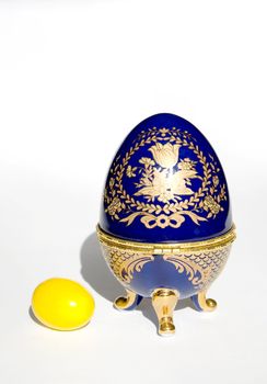 Faberge egg copy near real yellow Easter egg isolated on a white background