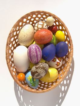 Easter eggs colored and decorated in wicker dish.