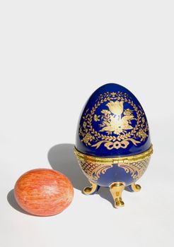 Orange Easter egg near copy of Faberge egg isolated on a white background