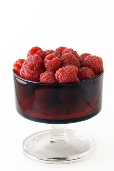 Vertical of vintage red serving glass filled with healthy and fresh raspberries.