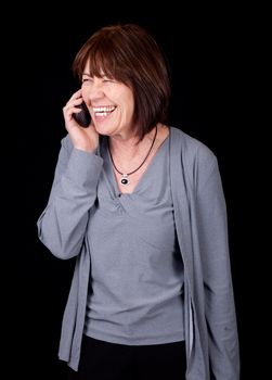 A businesswoman in her 50's is laughing while talking on the phone.