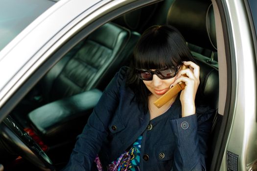 Attractive young woman calling by cellular phone in car