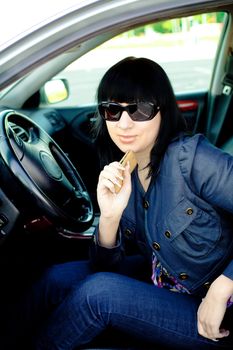 Beautiful young businesswoman with cellphone in her car after work