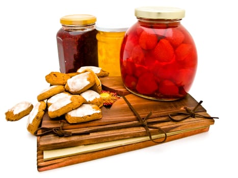 jars with jam and spice-cakes at ancient wooden desk against the white background