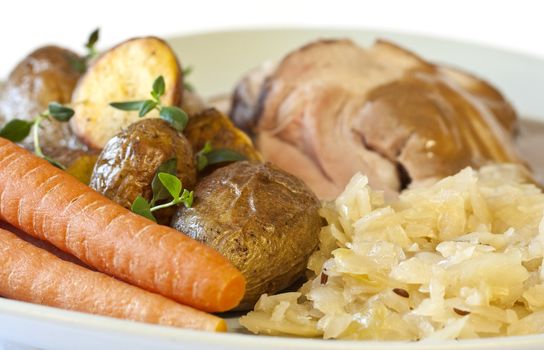 Traditional and delicious dinner; pork with sauerkraut, carrots, brown sauce, and fried potatoes