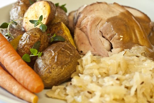 Traditional and delicious dinner; pork with sauerkraut, carrots, brown sauce, and fried potatoes