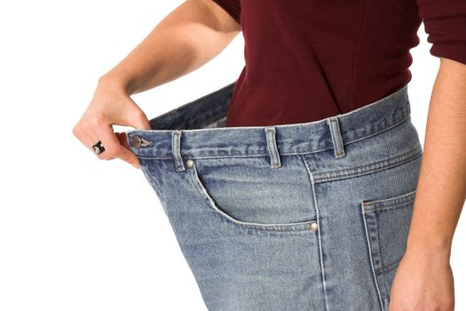 Female showing how much weight she has lost by wearing her old jeans that are sizes too big
