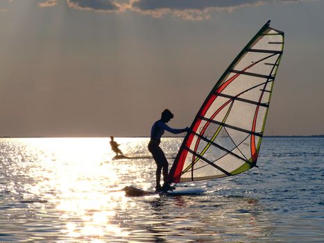 A women is learning windsurfing at the sunset