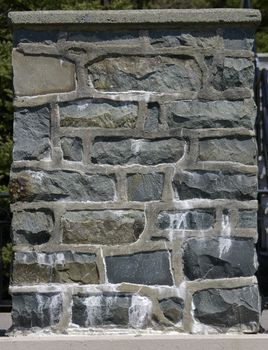 A post found in a park made of stone and concrete or cement.