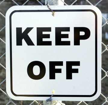 A warning sign on a fence telling people to Keep Off.
