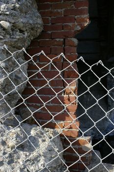 Crumbling concrete and brick walls behind a chain link fence.