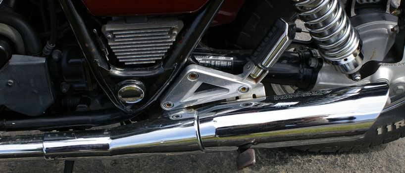 A view of a motorcycle exhaust and rear peg