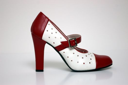 A side view of a red and white high heel on white.