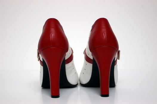 An end view of a red and white high heel on white.