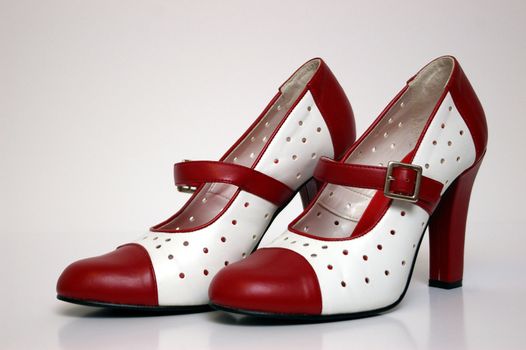 A side view of a pair of red and white high heels on white.