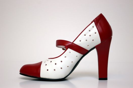 A side view of a red and white high heel on white.