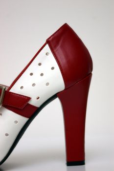 A side view of a red and white high heel on white.