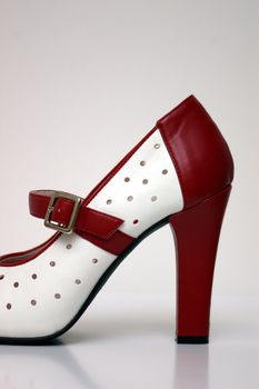 A side view of a red and white high heel on white.