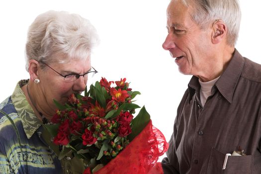 Senior couple where the woman is smelling the flowers that she has just received for valentines day