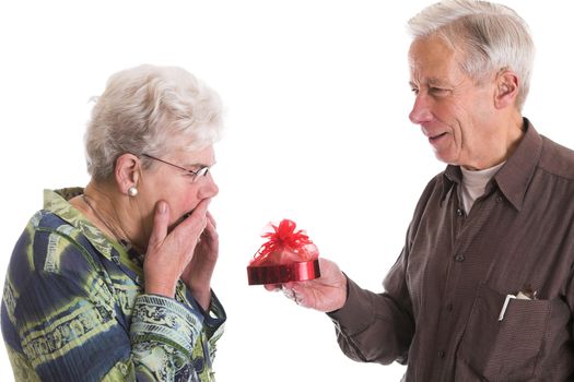 Senior man giving his wife a box of valentine chocolates; the wife looks a bit shocked