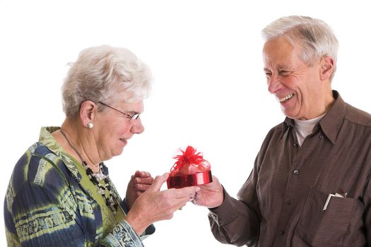 Cute elderly couple having fun together when the husband gives his wife a box of chocolate for valentines day